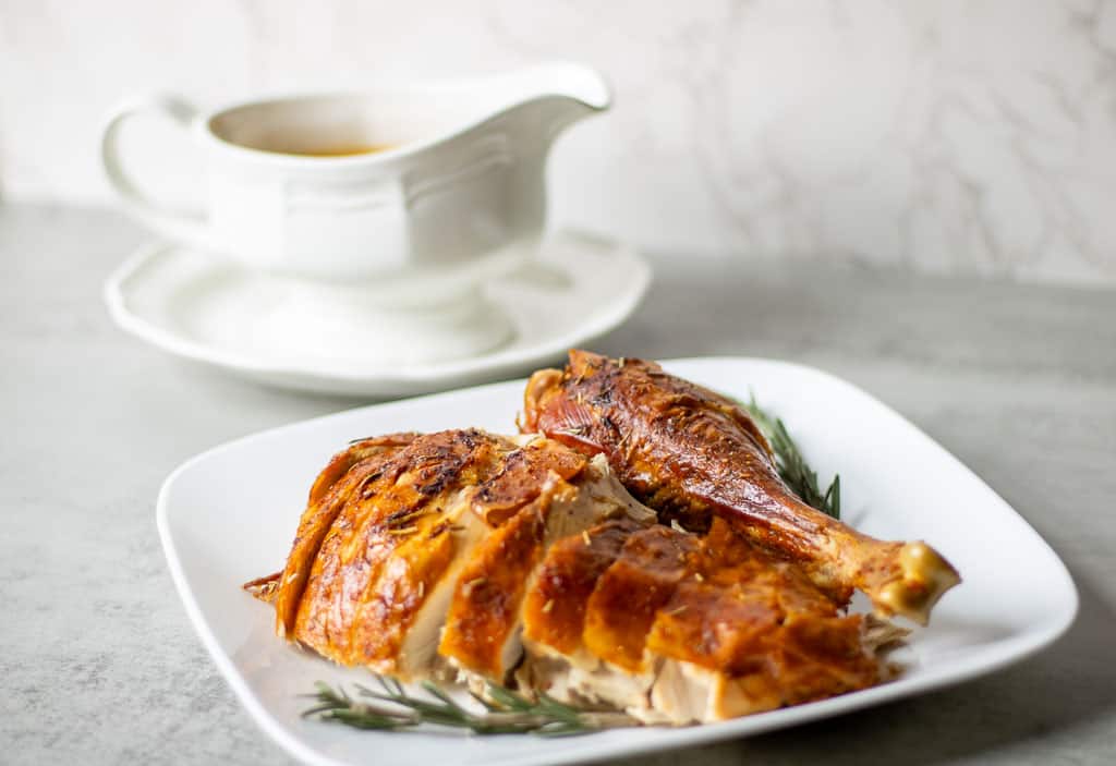 roasted pasture raised turkey on a plate with a gravy boat dish