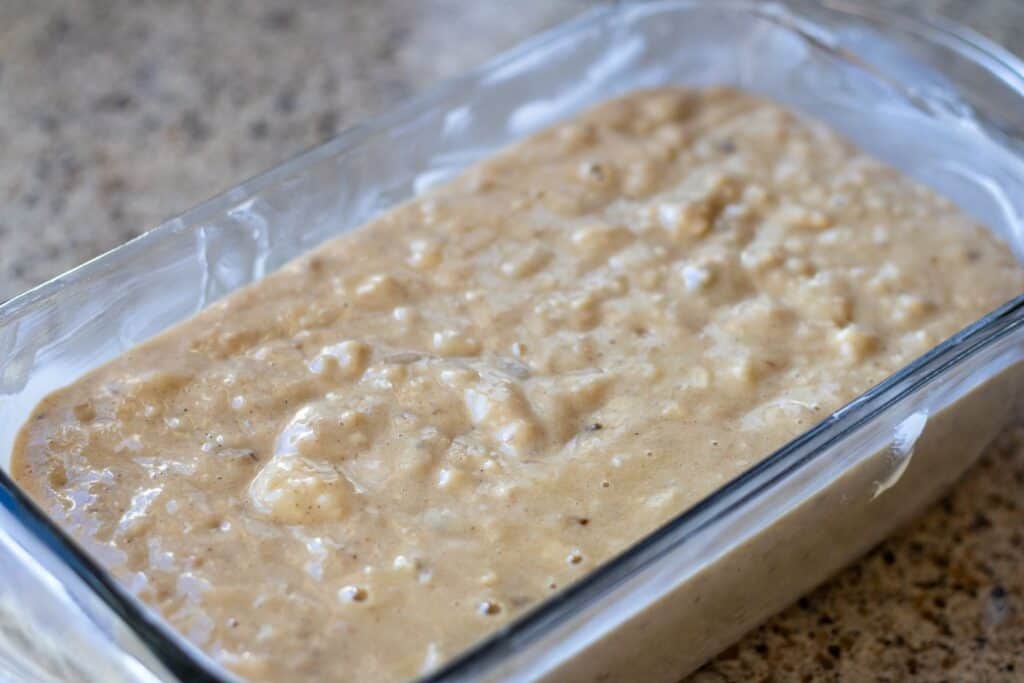 Sourdough banana bread batter in a greased 9x5-inch glass loaf pan.