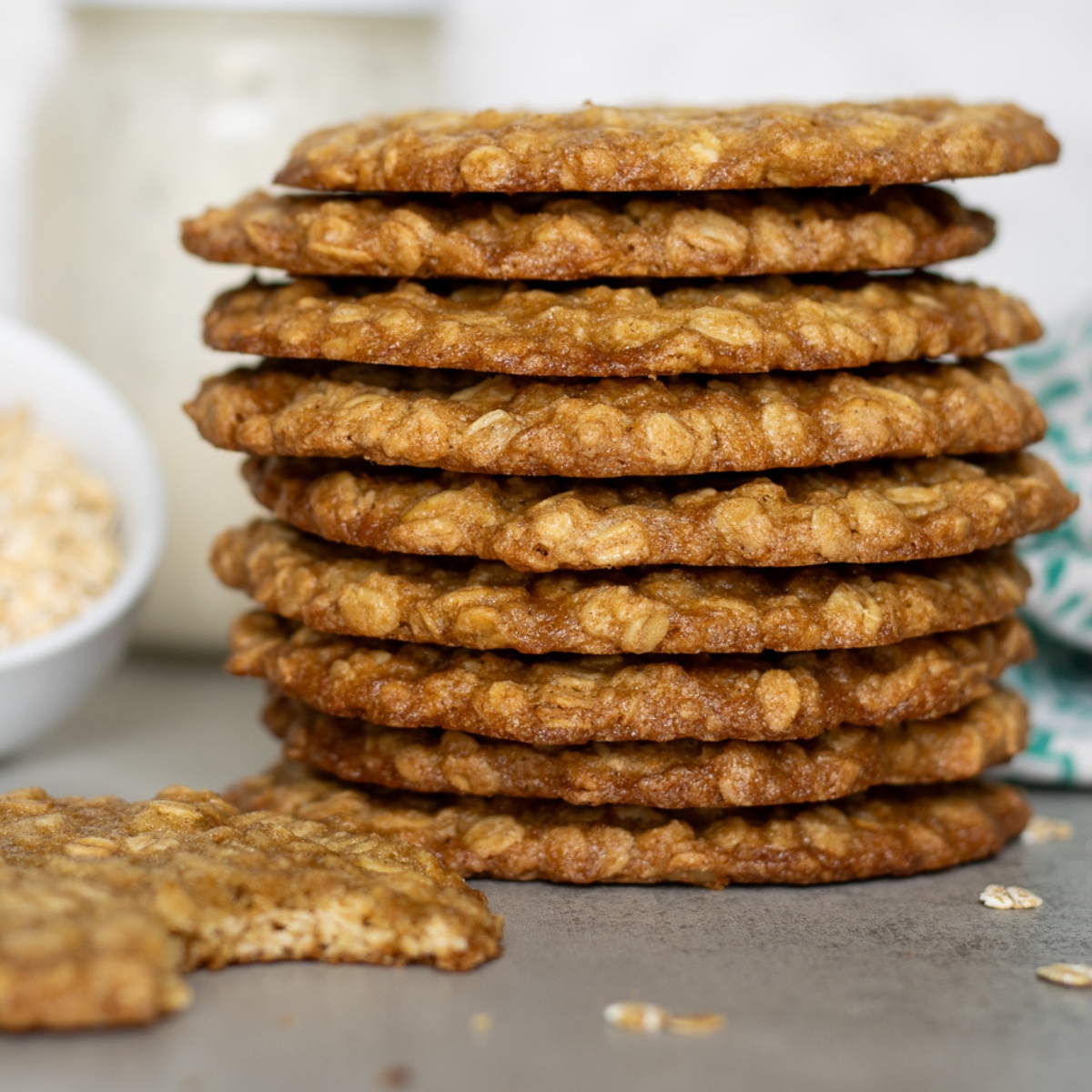 A stack of oatmeal cookies with a bowl of milk