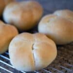 A batch of baked semmel rolls on a wire rack.