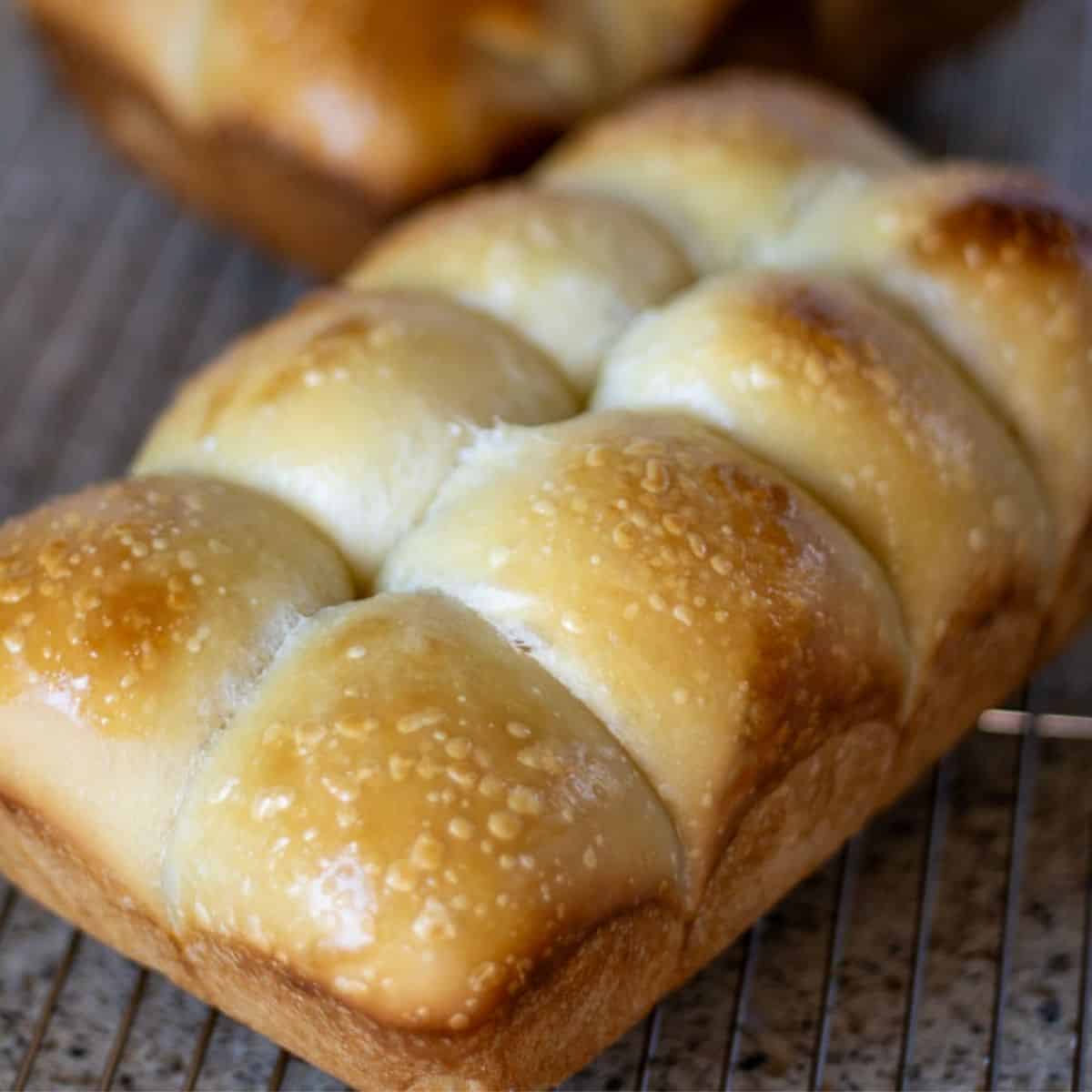 A loaf of sourdough challah bread on a wire rack.
