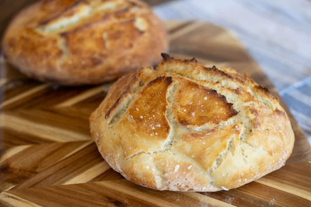 Two golden crusty loaves of sourdough bread resting on a cutting board.