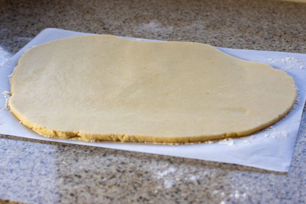 Shortbread cookie dough rolled out on a piece of parchment.