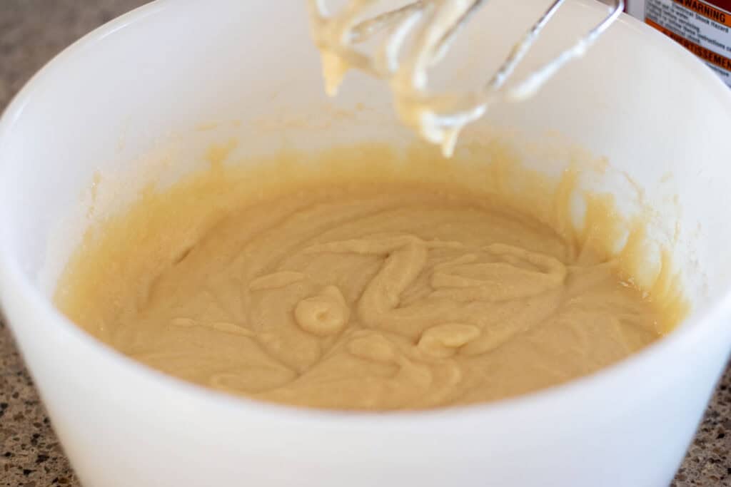 A bowl of sourdough cupcake batter mixed with handheld beaters.