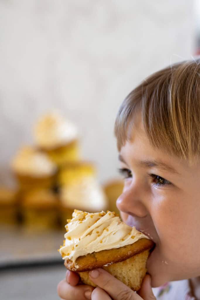 A little girl biting into a sourdough cupcake.