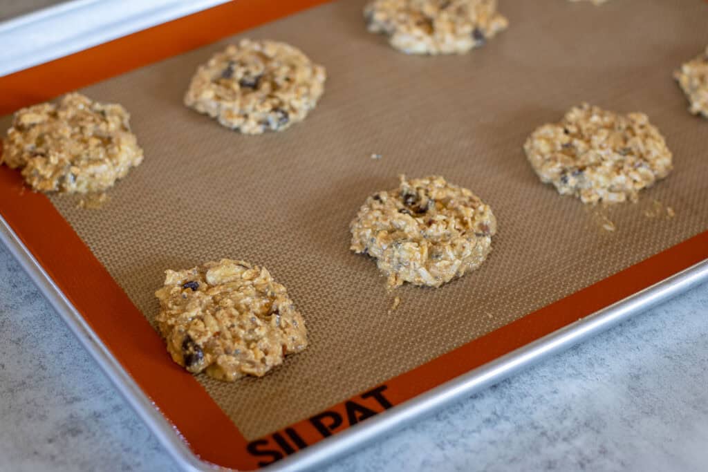 A baking sheet lined with a silicone baking mat with sourdough breakfast cookies ready to go into the oven.