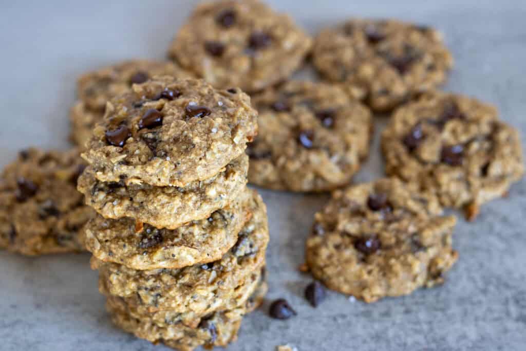 A baked batch of chocolate chip breakfast cookies with some stacked on top of each other.