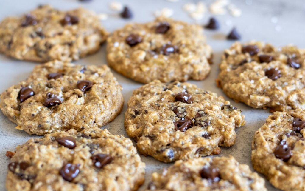A batch of baked sourdough discard breakfast cookies with some chocolate chips and flaky salt.