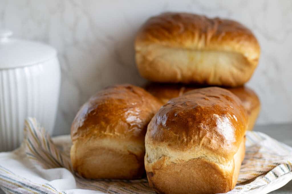 Four loaves of golden homemade bread on a platter made from a large batch bread recipe.