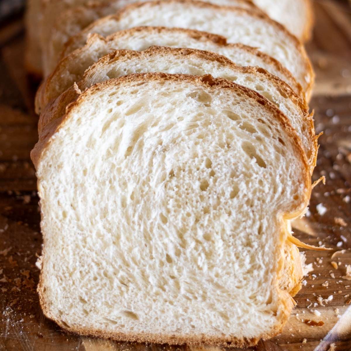 A whole loaf of soft sandwich bread sliced up and set on a cutting board.