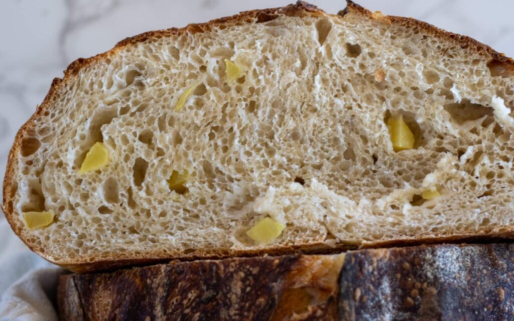 A close up view of the crumb of a loaf of sourdough apple bread cut in half.