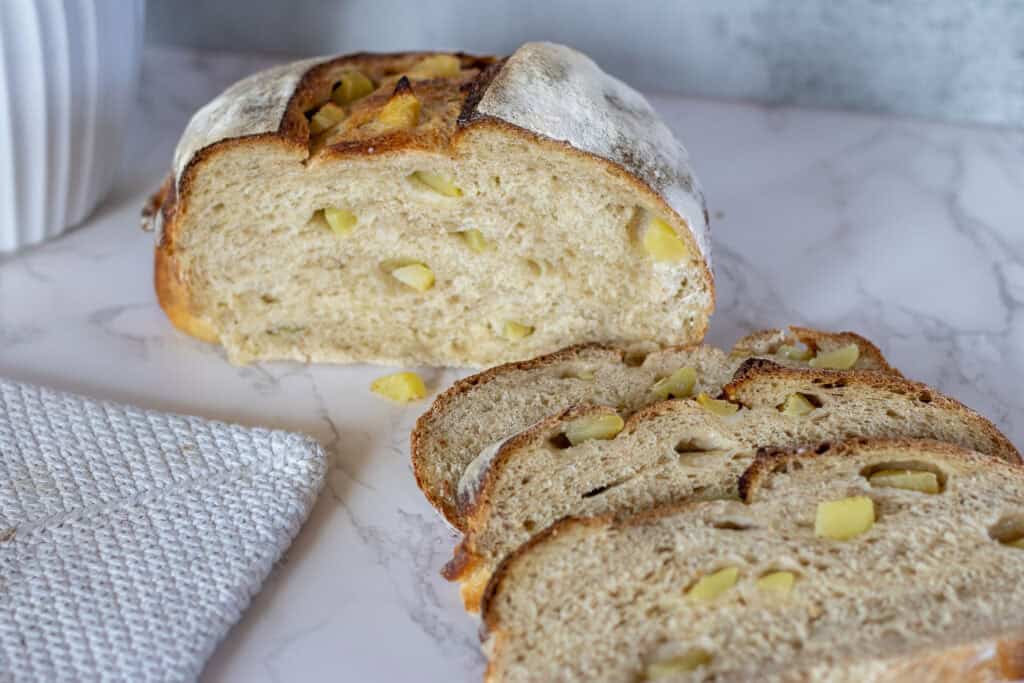 A loaf of fermented fresh apple sourdough bread sliced on a countertop.