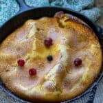 sourdough german pancake in cast iron skillet dusted with powdered sugar and topped with berries