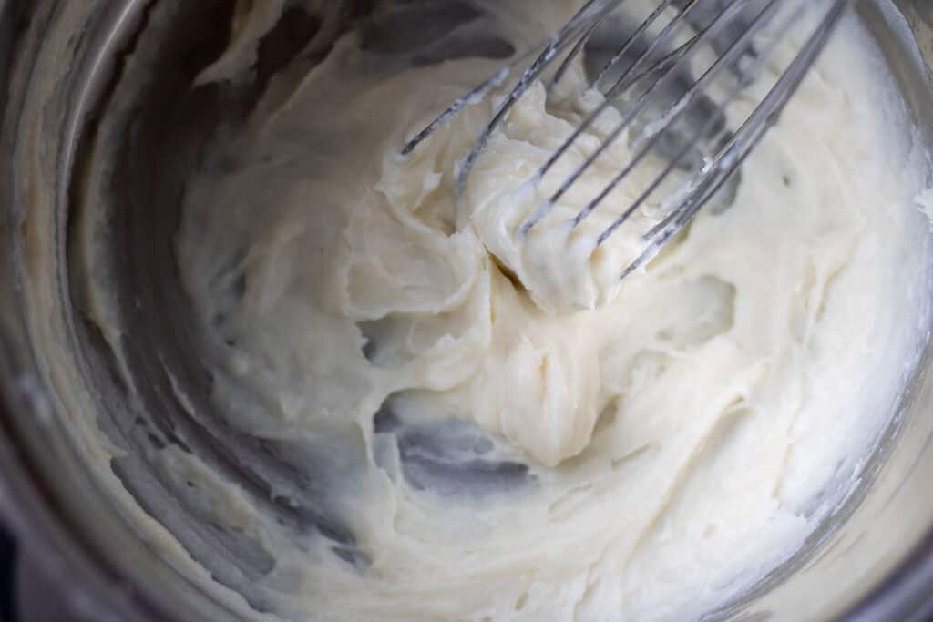 Cooking tangzhong paste in a saucepan over medium heat, whisking continuously until thickened for soft sourdough hot cross buns.
