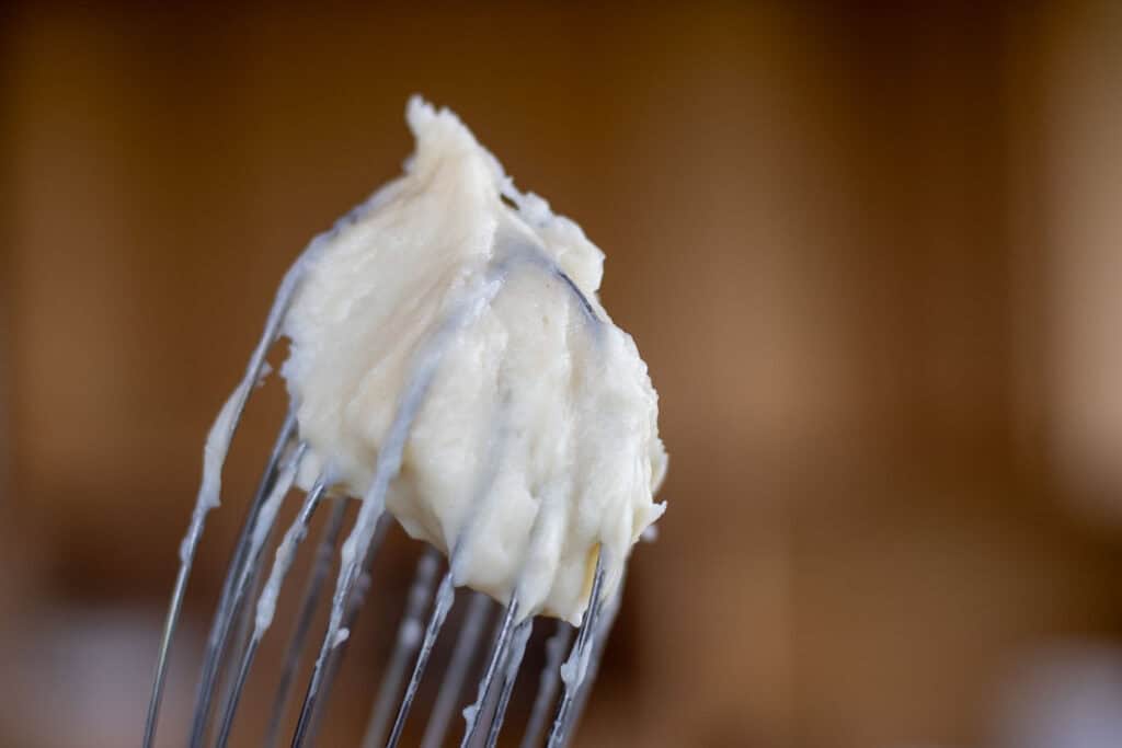 Close-up of smooth, thick tangzhong paste clinging to a whisk, ready to be added to sourdough hot cross buns dough.