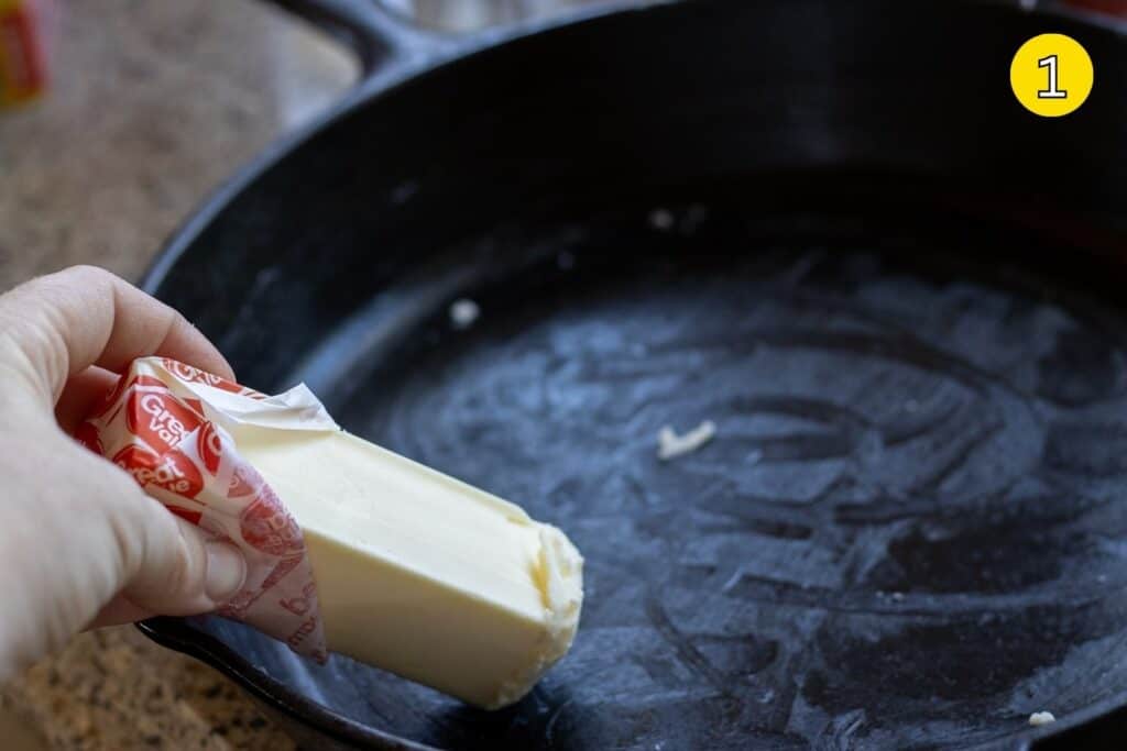 Spreading butter in a cast iron skillet to grease it before baking.