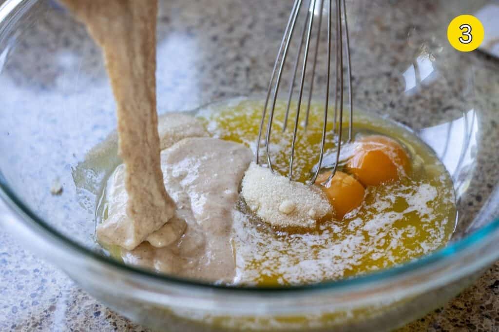 Whisking eggs, sugar, melted butter, and sourdough discard in a glass bowl.