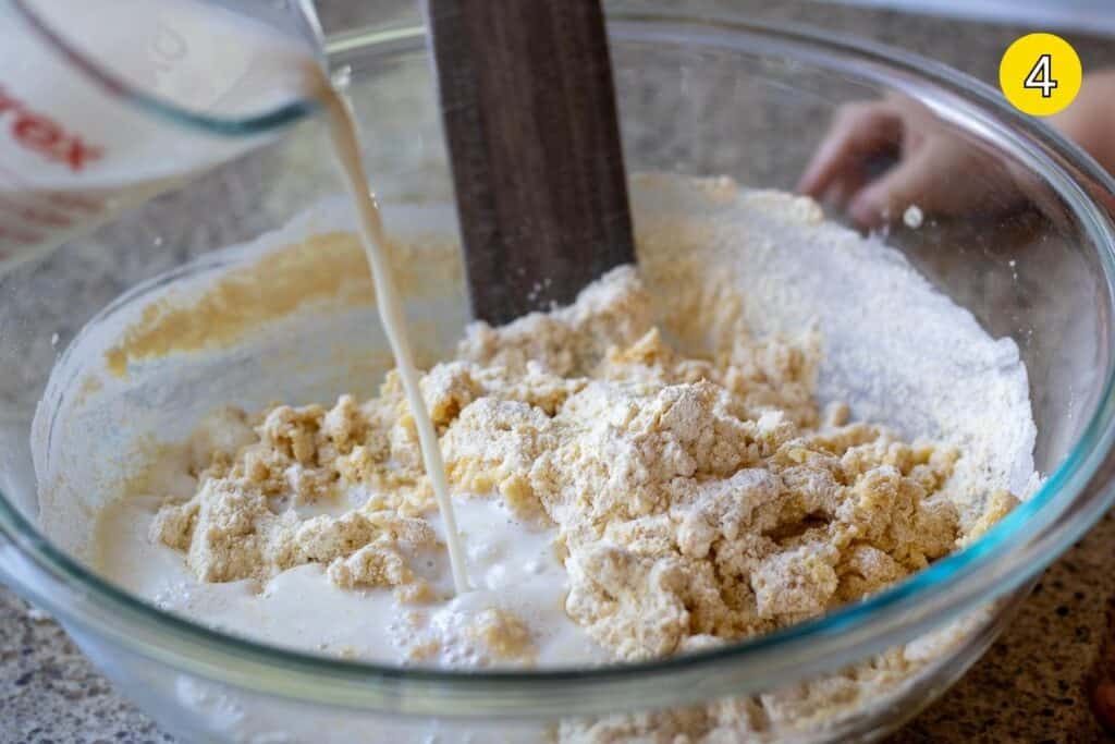Pouring homemade buttermilk into a bowl of sourdough cornbread batter.