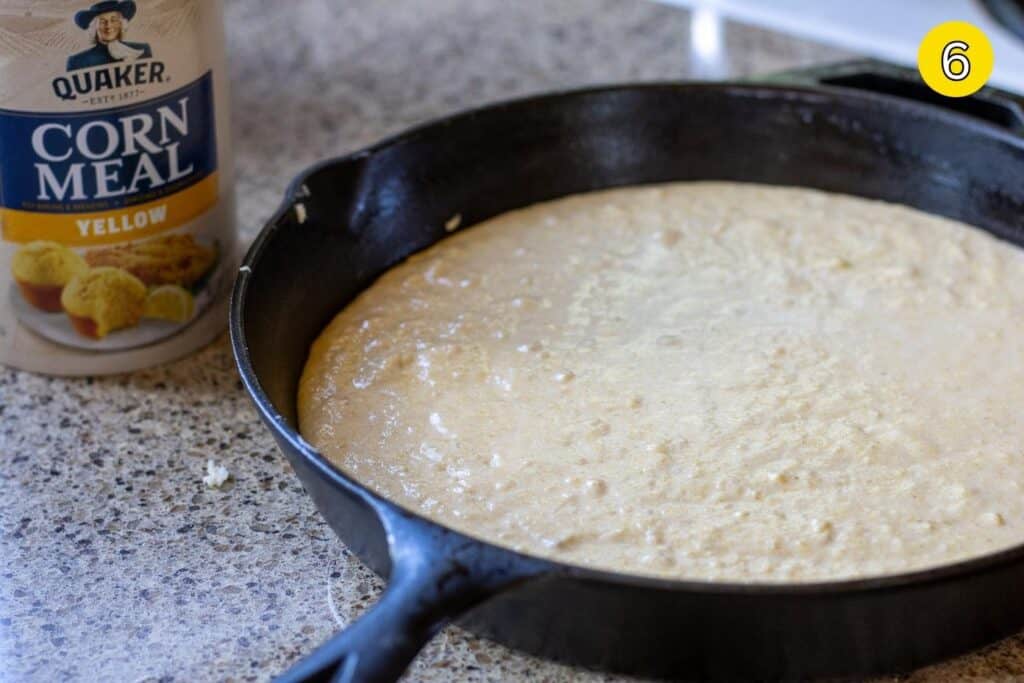 Cornbread batter poured into a cast iron skillet, ready to bake.