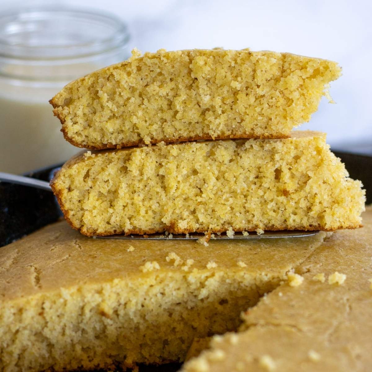 Close-up of sliced sourdough cornbread stacked in a cast iron skillet.