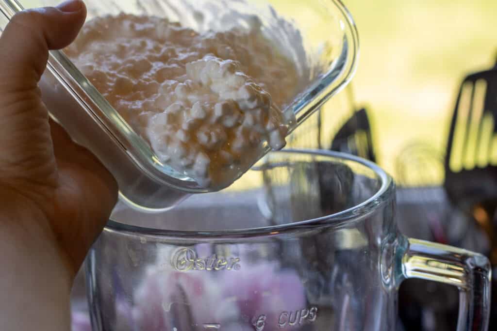 Pouring cottage cheese into a blender for pancake batter.