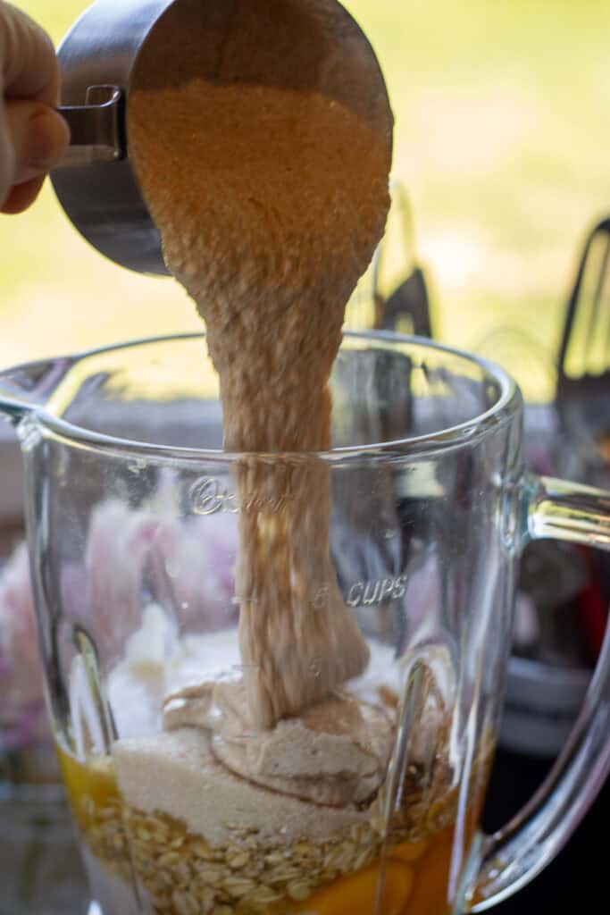 Adding sourdough starter to blender with pancake ingredients.