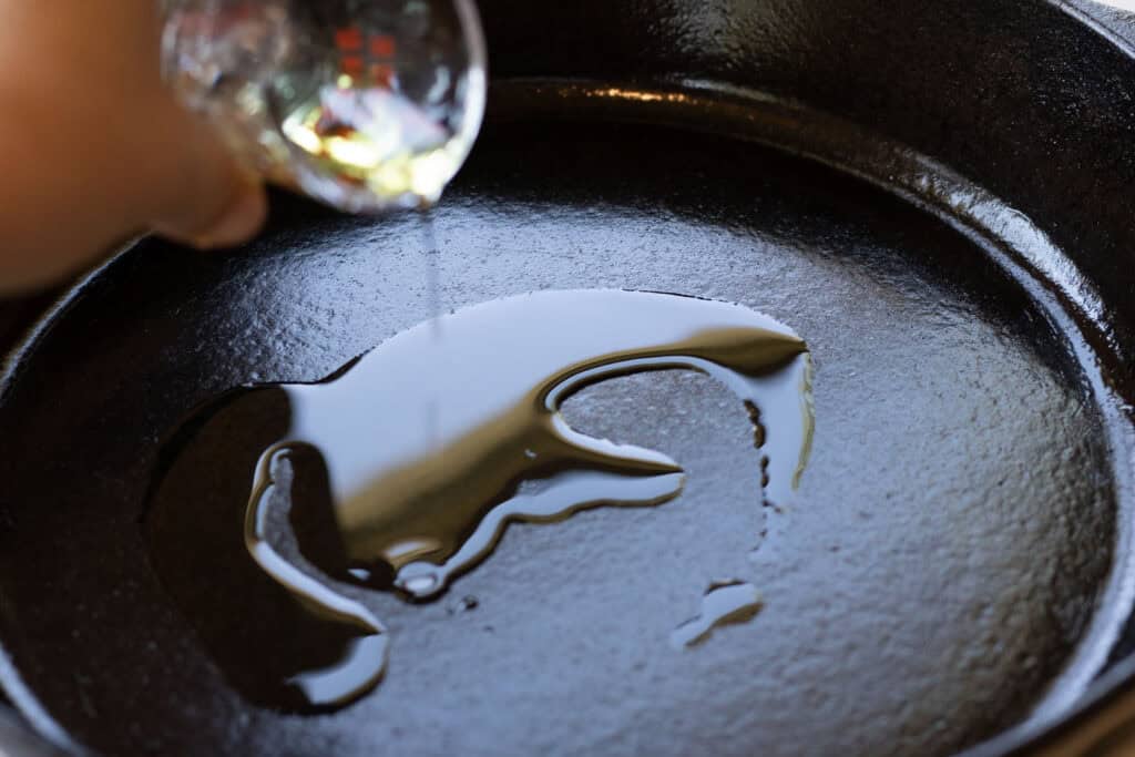 Pouring oil into a cast iron skillet for pancakes