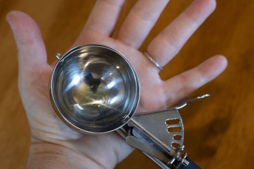 Large metal scoop held above an open palm to show pancake batter portion size