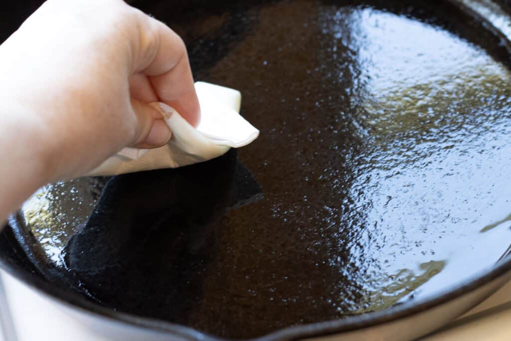 Wiping excess oil from skillet with a paper towel