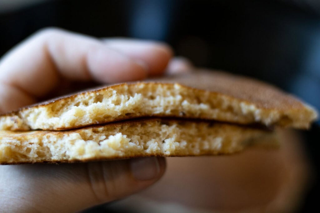 Fluffy inside of sliced pancake, held in hand.