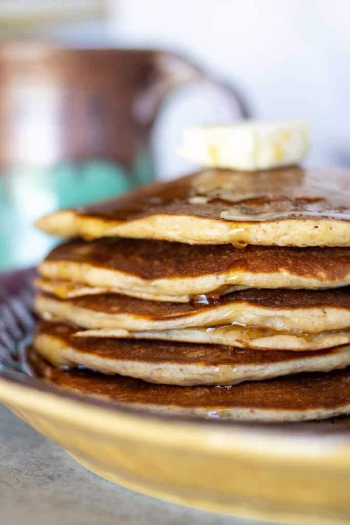 Stack of sourdough protein pancakes with syrup and butter on top.
