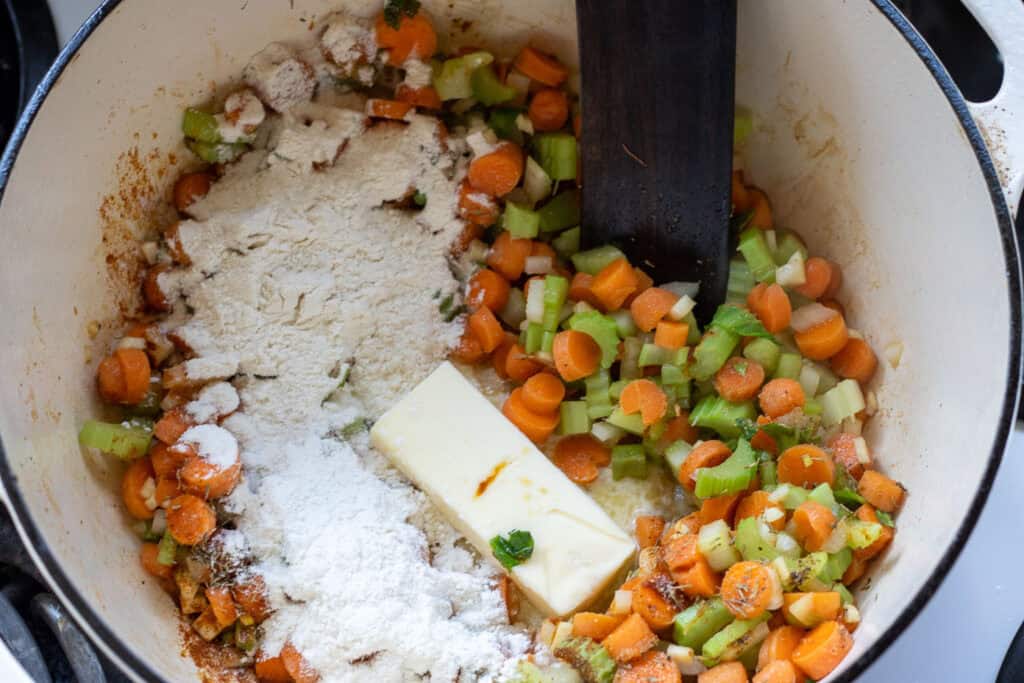 Butter and flour added to sautéed carrots and celery in a Dutch oven, beginning the roux.