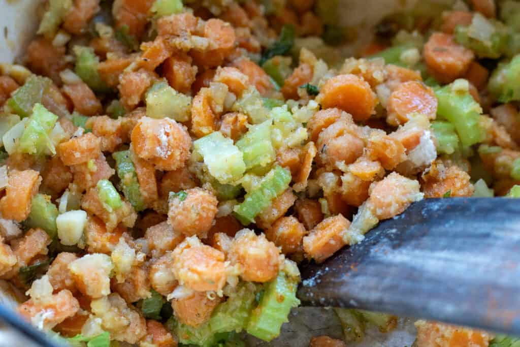Close-up of diced carrots and celery coated in a thick roux base, ready for broth.