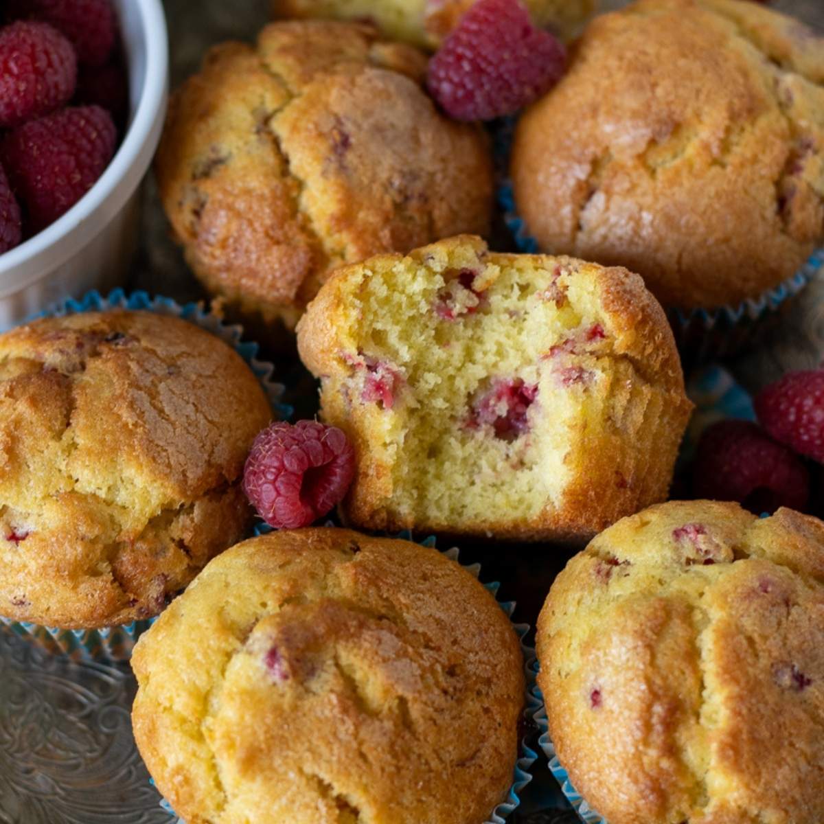 Overhead shot of raspberry sourdough discard muffins arranged on a vintage tray with fresh raspberries and lemon