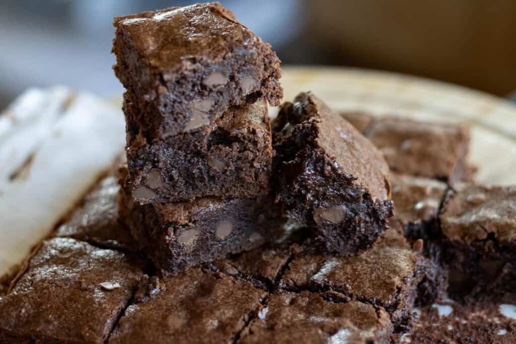 Three sourdough brownies stacked on top of a batch of brownies with another brownie leaned up against the stack.