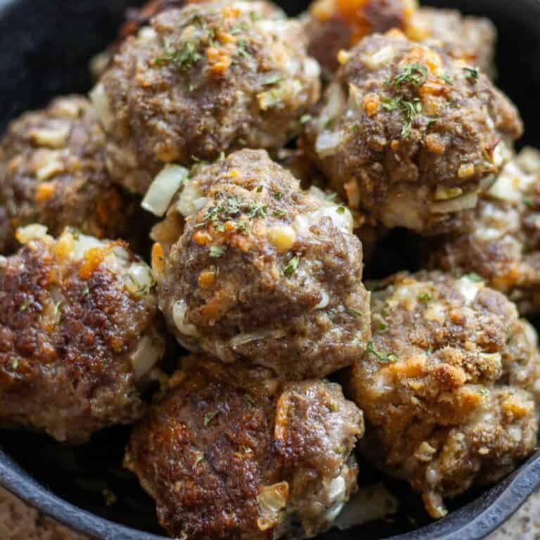 A small cast iron skillet piled full with sourdough discard meatballs baked to golden perfection.