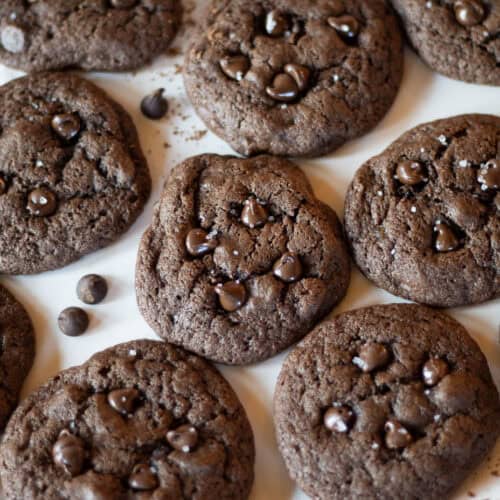 A freshly baked batched of sourdough double chocolate cookies with chocolate chips and flaky sea salt sprinkled on top.