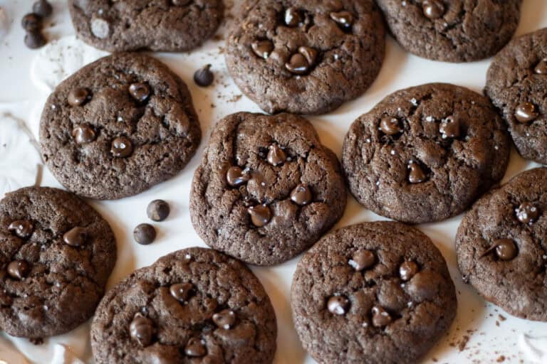 A freshly baked batched of sourdough double chocolate cookies with chocolate chips and flaky sea salt sprinkled on top.