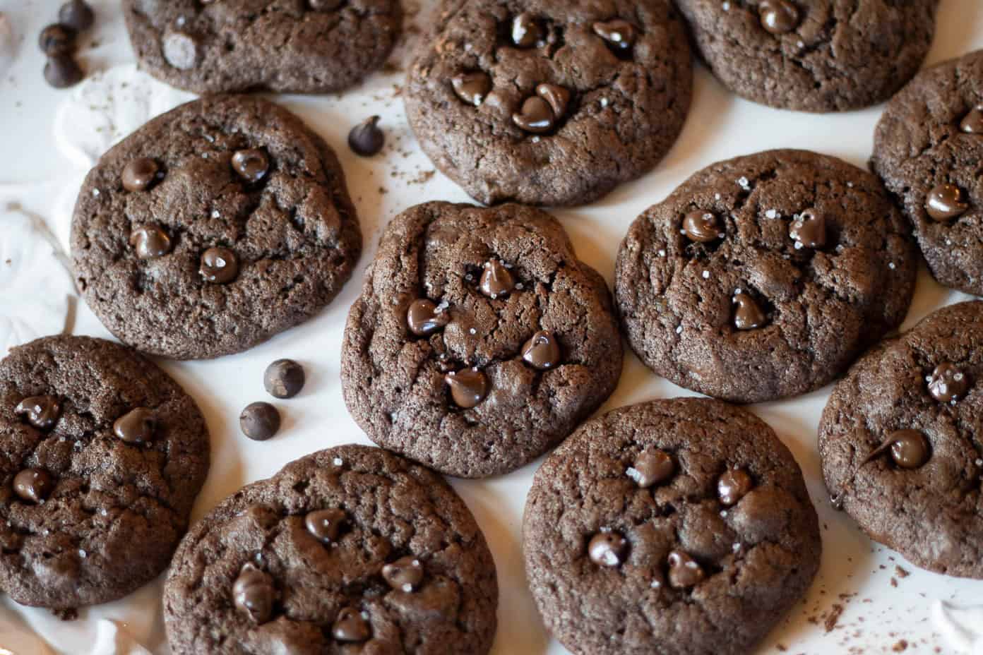 A freshly baked batched of sourdough double chocolate cookies with chocolate chips and flaky sea salt sprinkled on top.